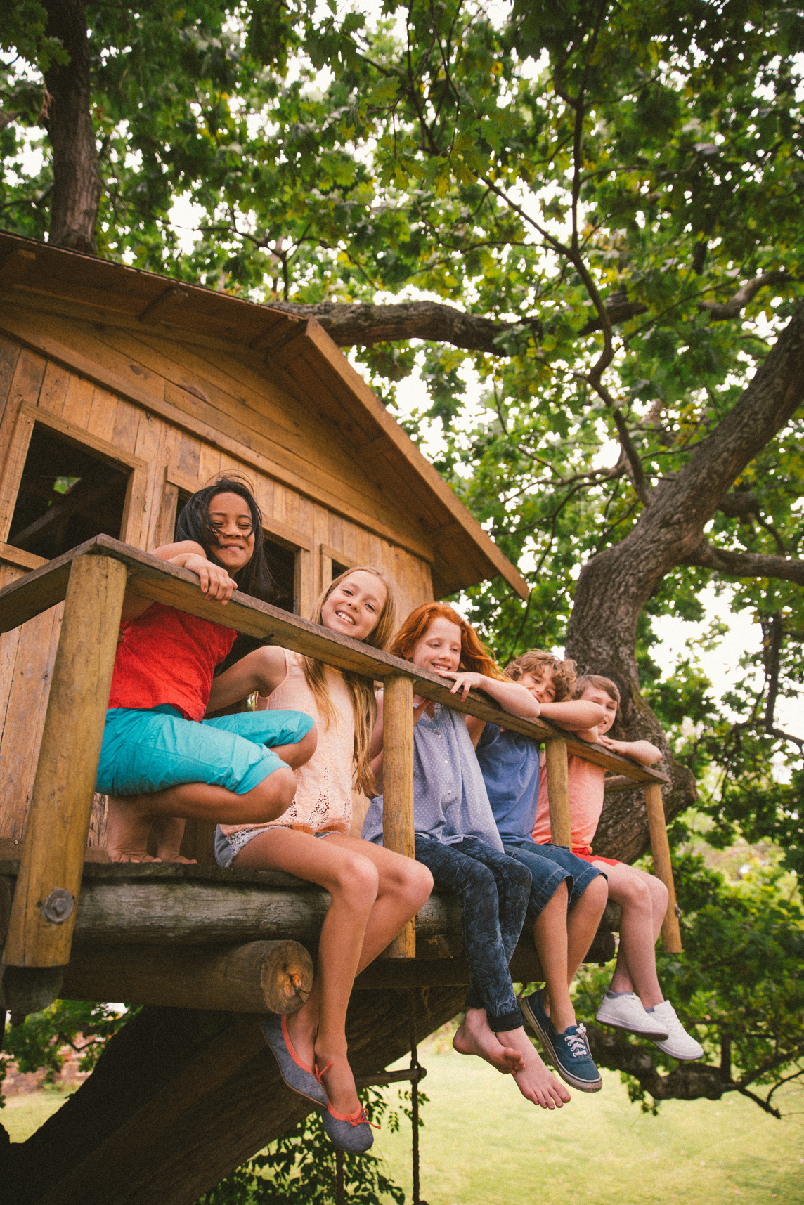Row of children sitting on a wooden treehouse